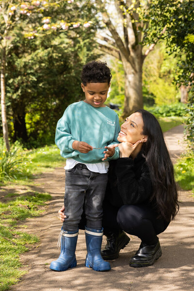 Joyful young boy and his mother sharing a tender moment in a blooming spring garden, beautifully captured by Suzy Slemen Photography.