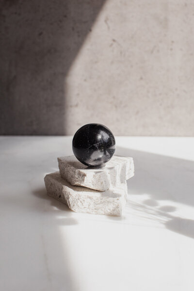 A high quality black tourmaline crystal sphere - our SSH ball, on a quartz slab.