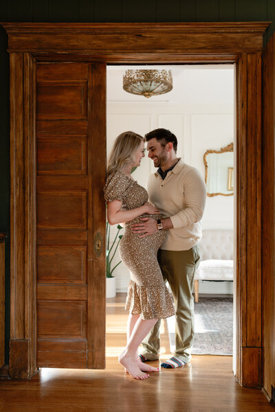 Maternity photo of a couple standing in a doorway.