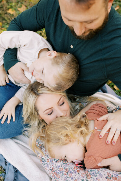 A family snuggles together for a group hug while laying for a candid moment