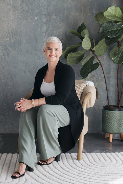 Amy Dewaele of South Rock Real Estate Group sits in a modern, neutral-toned space, smiling warmly.