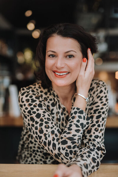 woman in leopard print blouse smiling to a camera