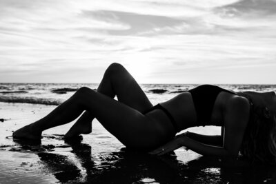 Bare silhouette of a woman against the backdrop of a golden sunset at the beach