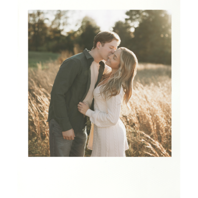 a couple in a wheat field for their engagement shoot fiance kissing the other on the cheek