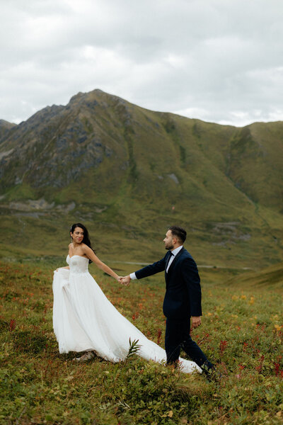 Couple standing on the edge of an Alaskan cliff, overlooking the ocean.