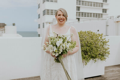 Jessica smiles in her wedding dress holding a goregous Molly in the Sky Bouquet.