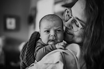 Justine Birth Photographer with her 6th baby over her shoulder during newborn photography session at home