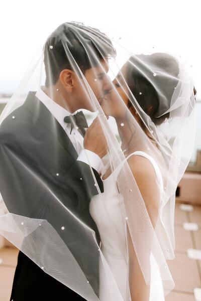 Newlyweds Kissing Under Pearl Veil