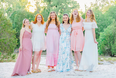 college girls in pastel colored dresses in Klondike park smiling at the camera