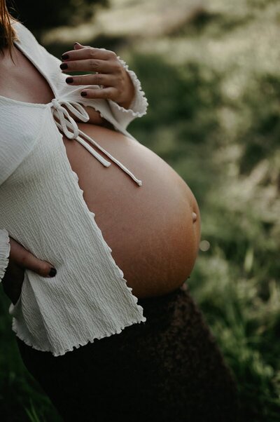 Gravid mage syns under en öppen blus.