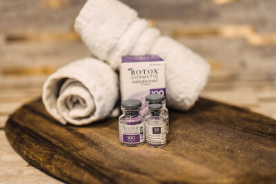 botox bottles and box sitting on a wooden tray next to white towels