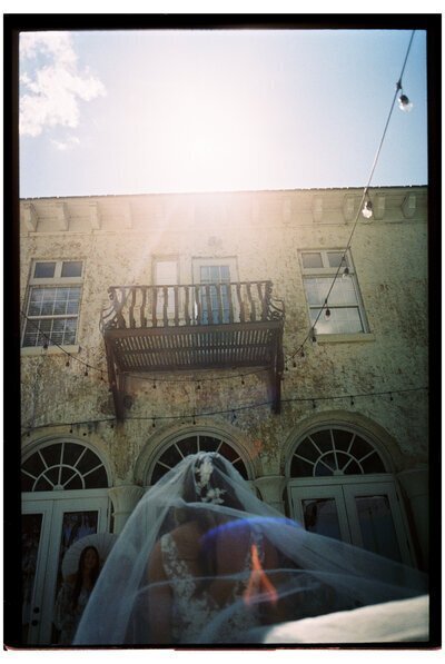 Bride looking at balcony by film wedding photographer Noble Photo Co