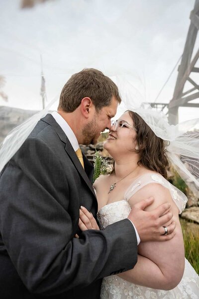 Bride and groom rubbing noses under her veil 