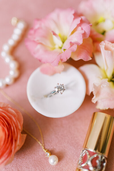 Close up of engagement ring surrounded by jewelry and pink florals