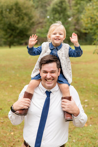 Dad holding toddler daughter on his shoulders