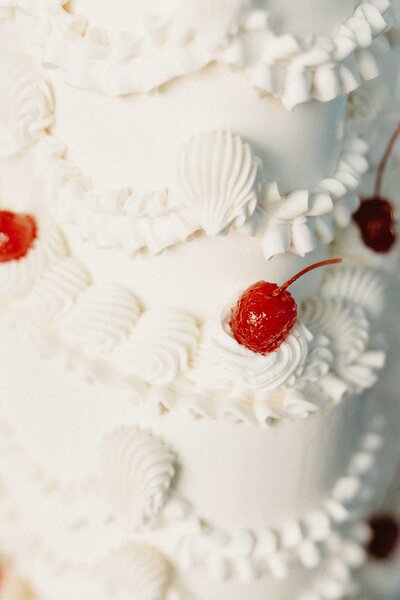 Close-up of a white wedding cake topped with maraschino cherries