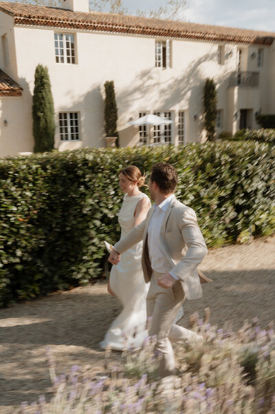bride and groom running together through open field during elopement