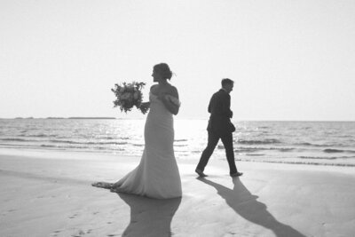 bride and groom explore a sandy beach in Gros Morne at sunset