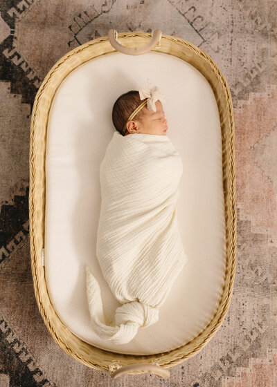 Newborn baby resting in a Moses basket during a cozy in-home newborn session in Los Angeles.