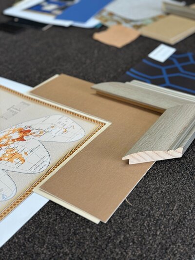 Framing materials selected for large world map artwork in curated dining room redesign.