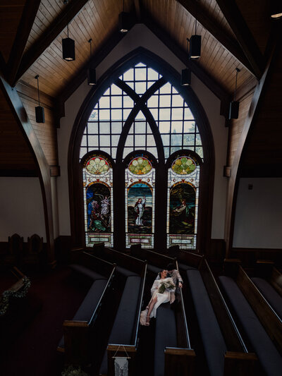 An intimate overhead shot of a couple lying on a spiral staircase, wrapped in warm shadows and architectural lines. The moment feels cinematic, like a scene from a vintage romance.