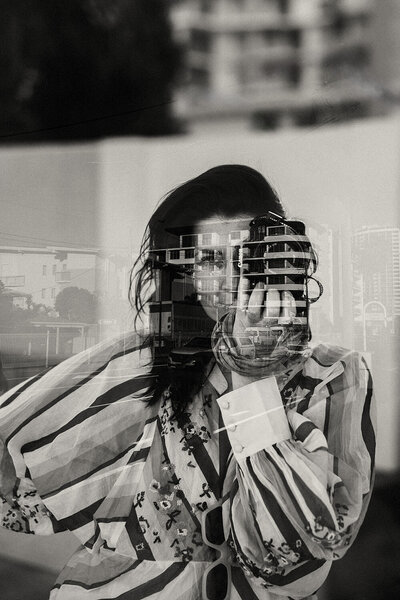 Black and white image of lady holding a camera, branding photoshoot on the Sunshine Coast