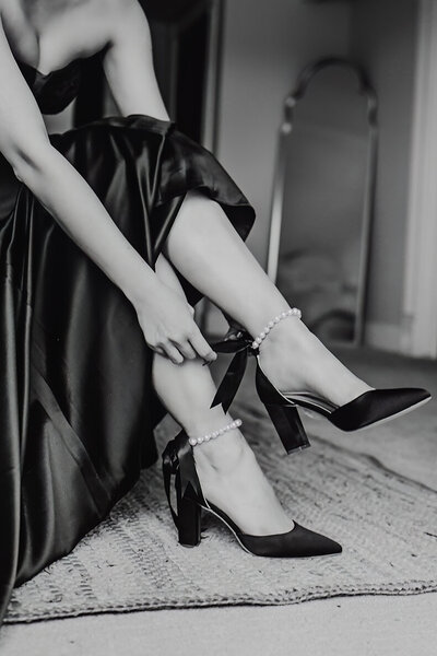 a close up photo of a bride putting on her wedding shoes