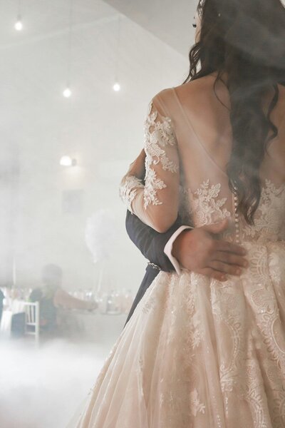 Bride and groom sharing their first dance in a dreamy, fog-filled room