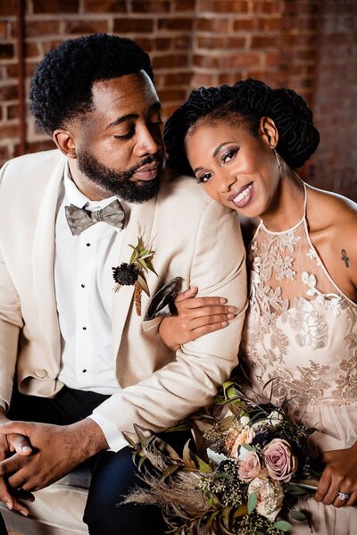 Couple eloping in historic venue in Nashville. He's smiling at her and she's looking at the camera. They are wearing warm champagne tones.