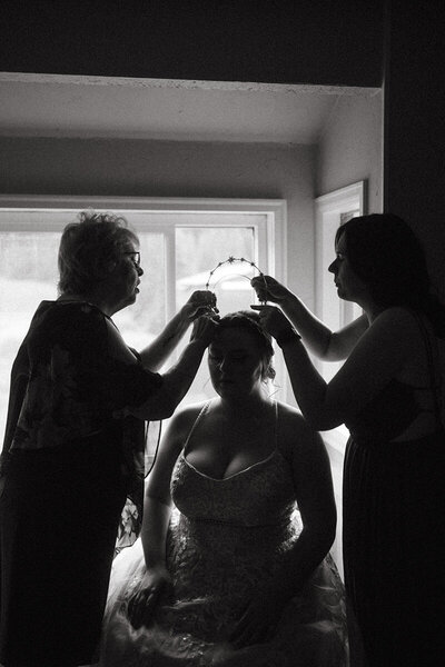 Family helps bride put on bridal crown in airbnb