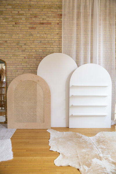 Three wooden arches of various sizes side by side, one caned, one plain white, and one with shelves.