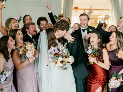 Flash photo of groom carrying bride through the line of their wedding guests while silver streamers fly around them