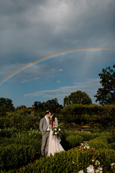 groom kissing bride under a rainbow