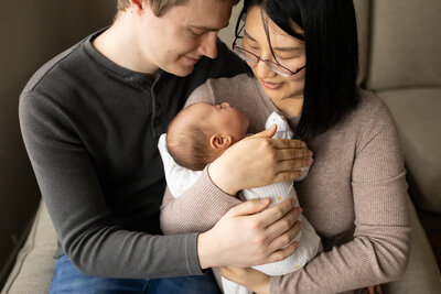 newborn sleeping soundly in parents arms. 