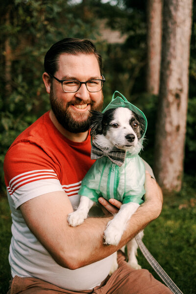 Bryan of O & B Photo Co. holds his dog who is wearing a tiny raincoat. 
