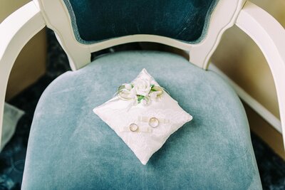 Close-up of wedding rings delicately displayed on a luxurious blue velvet chair, symbolizing love and commitment.