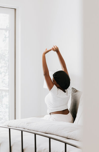 An image of a black woman stretching on a bed on a website for intensive therapy for moms in early motherhood in Massachusetts and Texas