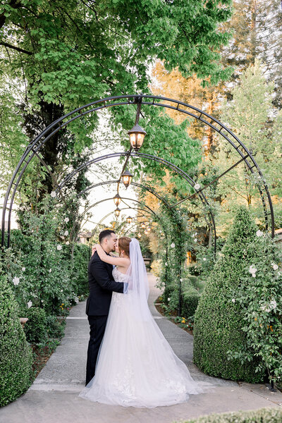 Bride and groom share a kiss in the lush tunnel on the English Garden side at Wolf Lakes Park