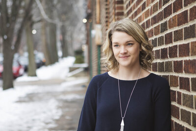 Laura outside in snow next to brick wall