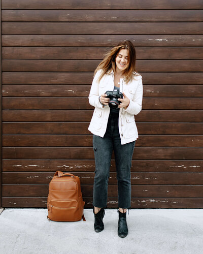 Headshot woman standing against brown wall with backpack looking at camera in Tampa Bay, Florida Nadine B Photography