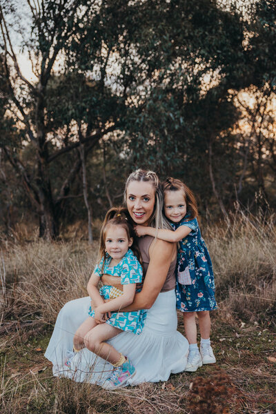 Mum-with-her-two-daughters-snuggled-looking-At-Camera