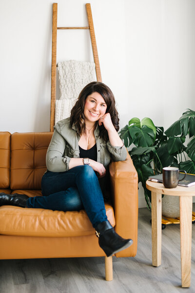 A woman smiles from her brown leather couch