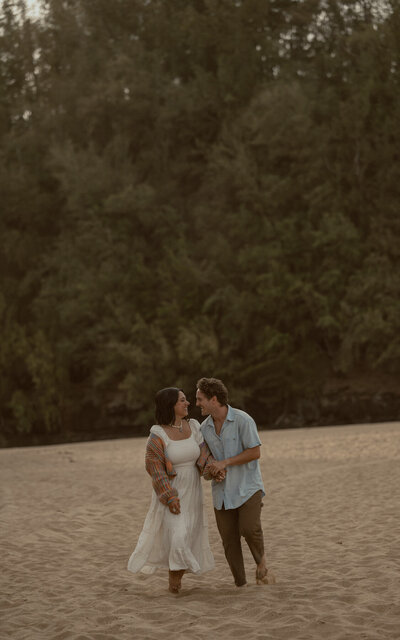 bride and groom holding hands while groom kisses her head with the rocky coastline of Big Sur as a backdrop