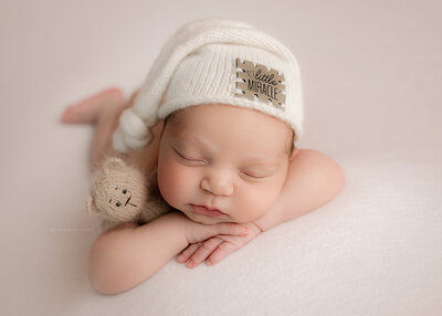 baby boy wearing little miracle hat holding baby bear for newborn portrait