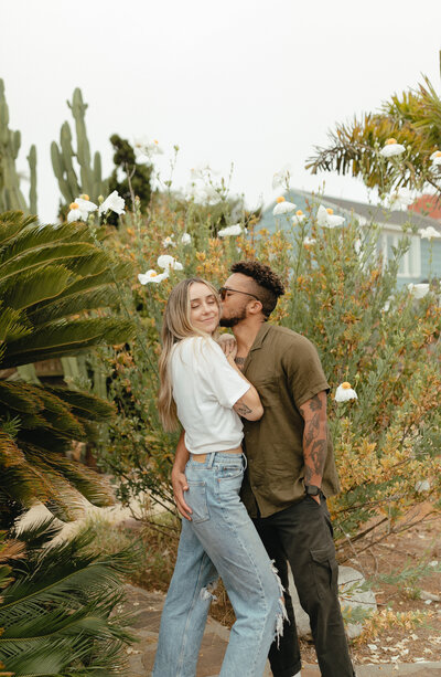 couple kissing in front of greenery in san diego california