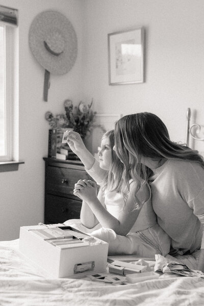 a mother and daughter moment looking through old family heirlooms in a bedroom