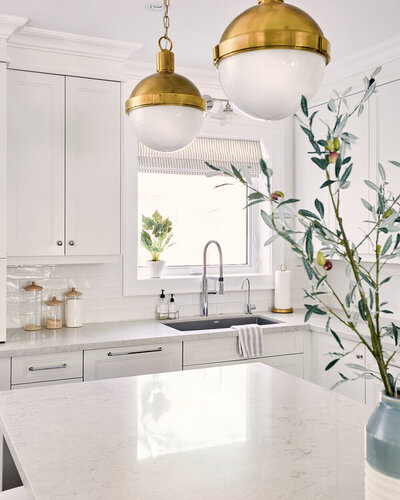 bright white coastal kitchen quartz marble counters subway tile backsplash chrome accents gold lighting