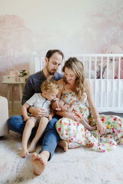 family cuddles their newborn in the nursery