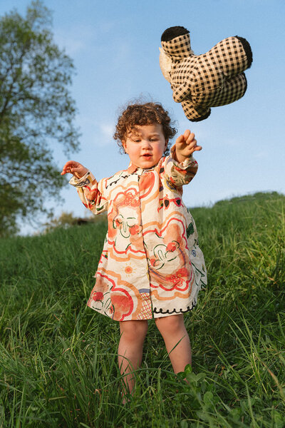 Little girl throwing toy outside in the grass