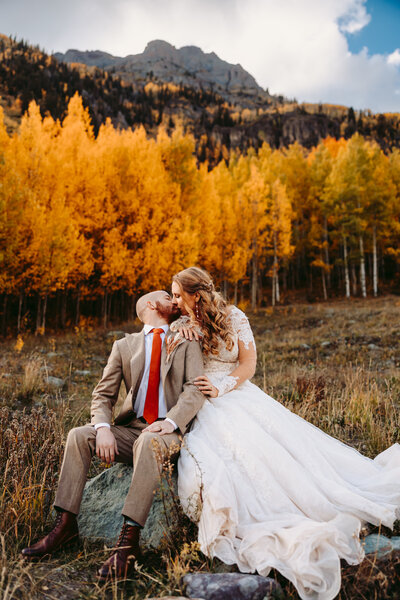 A couple kiss underneath golden aspen trees at a fall elopement in Ouray.